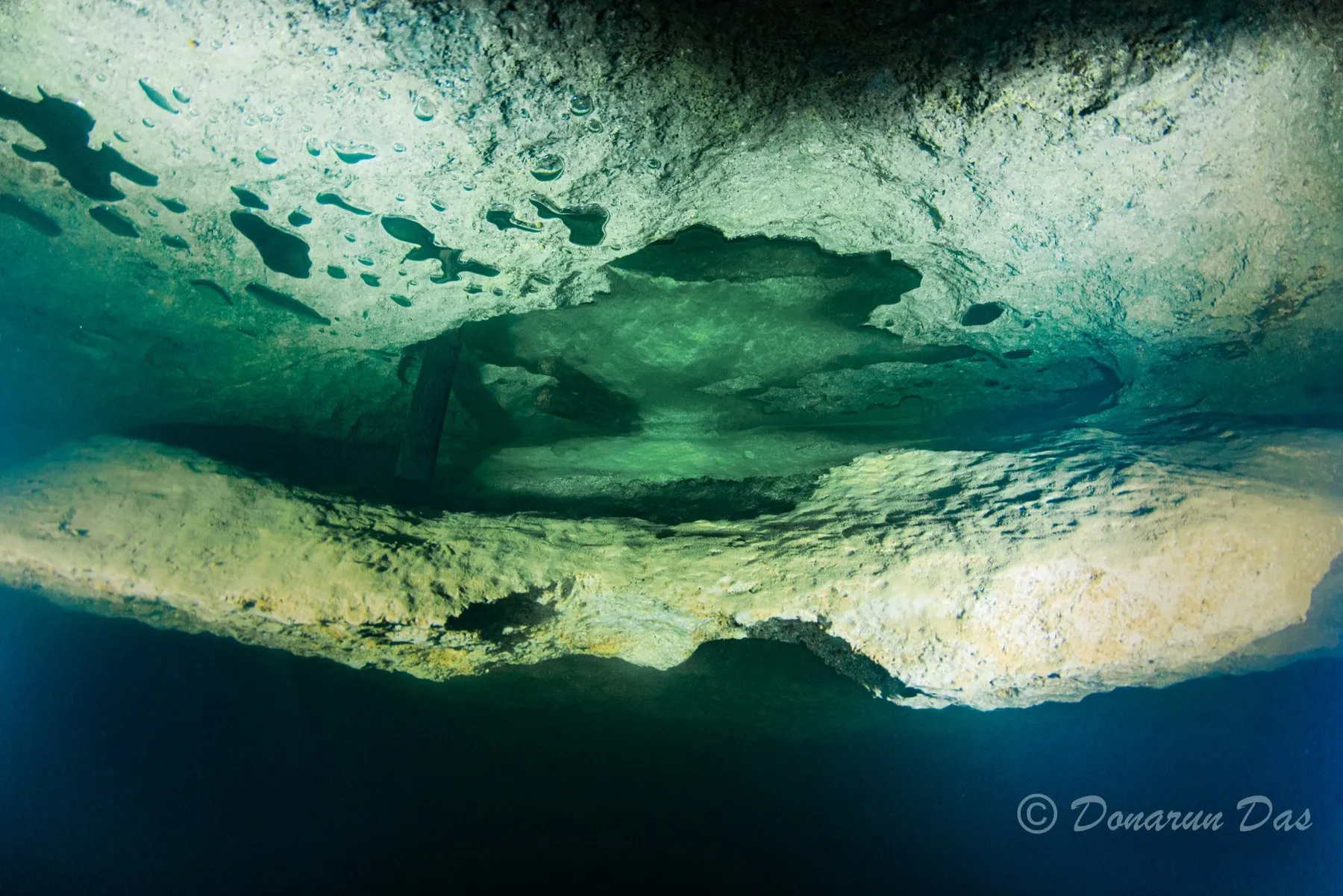 Underside of a limestone ledge with pockets of trapped exhaust gas against the rock, seen from below